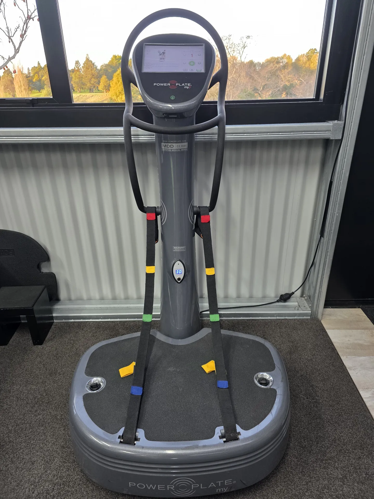 Grey Power Plate My7 upright machine with a touchscreen and training straps